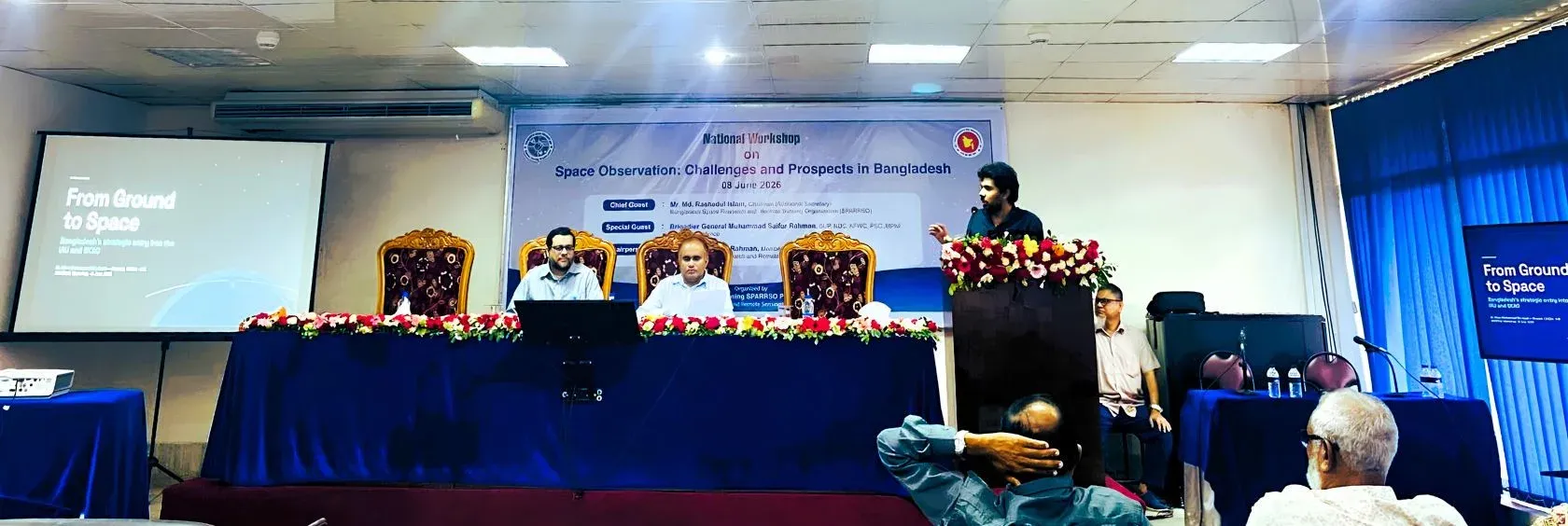 Dr. Khan Muhammad Bin Asad delivering the astrophysics keynote at the podium, beside a screen reading “From Ground to Space”.