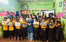 Chayatol students holding up their Sun and eclipse drawings with a Durbin instructor at the close of the outreach session.