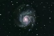A face-on spiral galaxy surrounded by foreground stars against a dark sky.