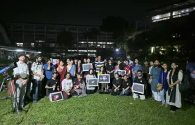 Participants and Durbin volunteers gathered on the TSC lawn at night, several holding framed astrophotographs, with a telescope at the left of the frame.