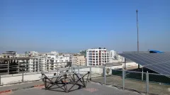 The TART radio-telescope antenna array on the rooftop of IUB's academic building, with the city skyline behind.